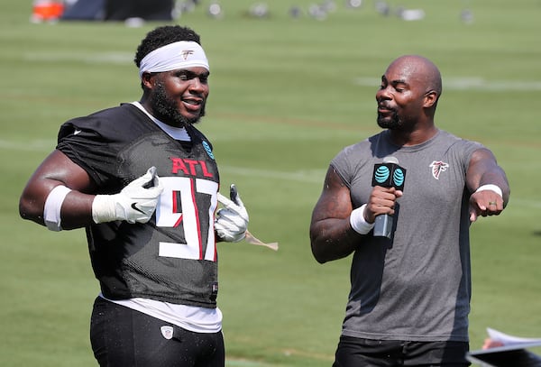 Falcons defensive lineman Grady Jarrett (left) points out his jersey number while clowning around with running back Mike Davis during interviews after the first day of practice during training camp Thursday, July 29, 2021, at the team's training facility in Flowery Branch. (Curtis Compton / Curtis.Compton@ajc.com)