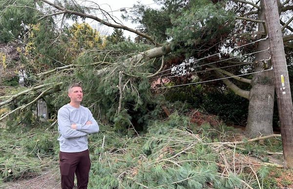 Brett Gordon of Seattle talks with a neighbor as he stands near a large branch sheared off from a tree during Tuesday night's "bomb cyclone," weighing down power lines in the Wedgwood neighborhood of Seattle, Wednesday, Nov. 20, 2024. (AP Photo/Gary Roundtree)