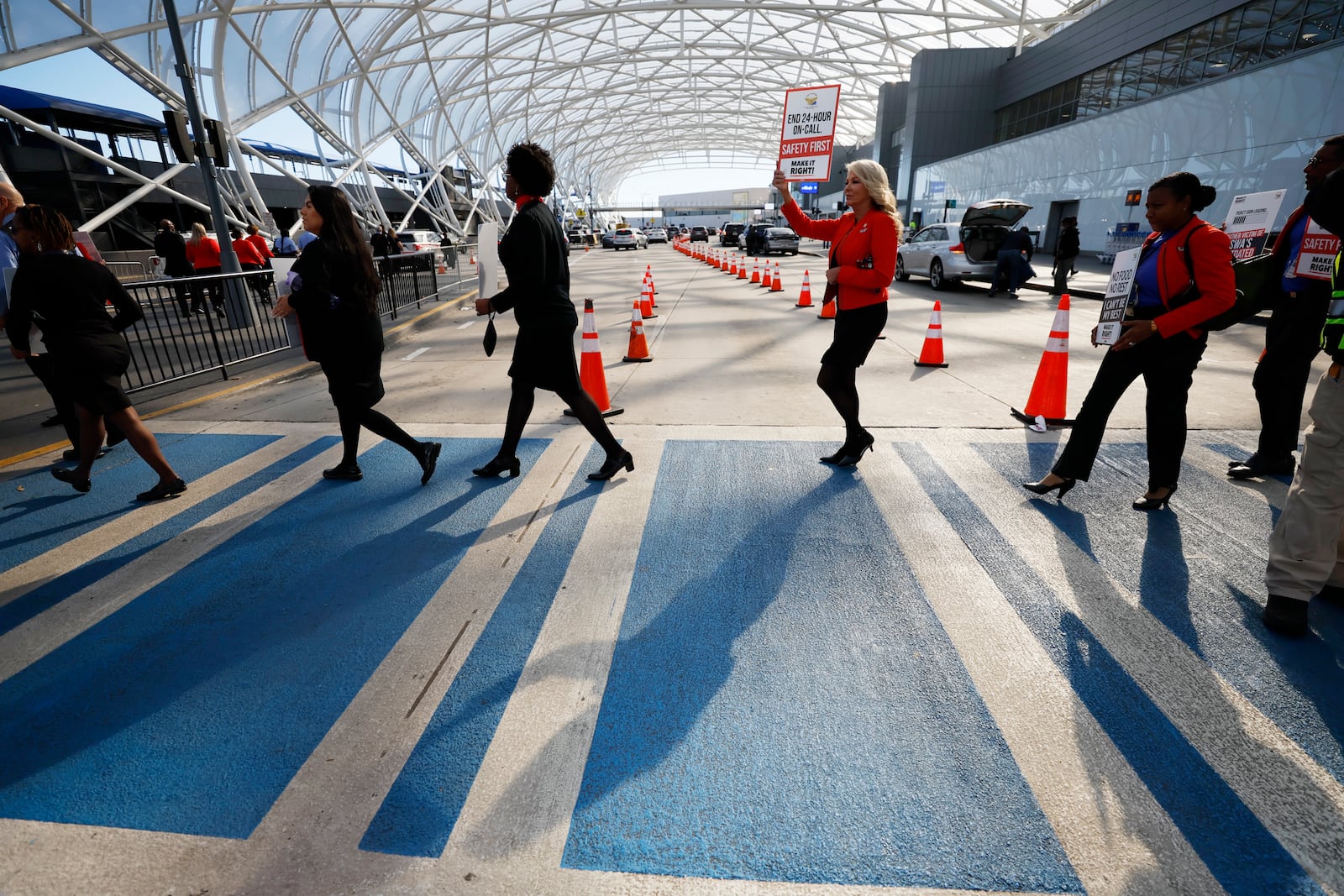 A group of Southwest flight attendants crosses the path to reach the median sidewalk to protest outside the North Terminal at Hartsfield-Jackson Atlanta International Airport on Tuesday, September 27, 2022. The Atlanta group joined Southwest Airlines flight attendants at 11 bases across the country to demand change for their workgroup. Miguel Martinez / miguel.martinezjimenez@ajc.com 