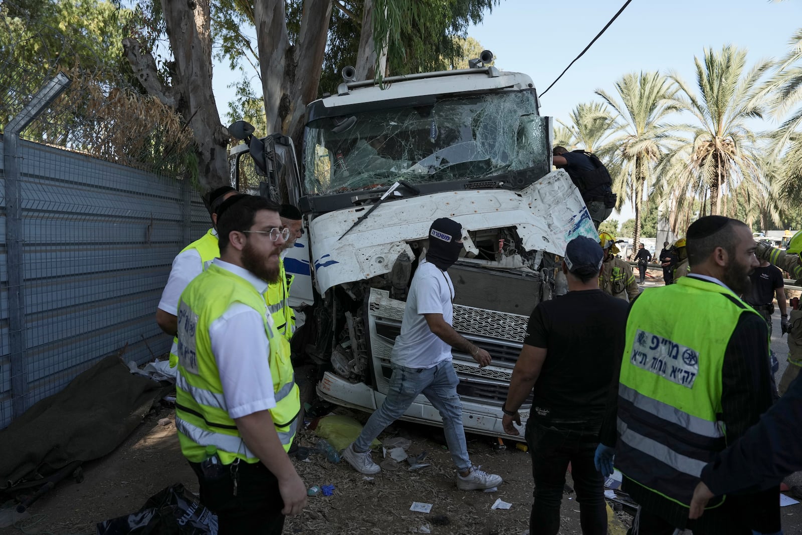 Israeli police and rescue services inspect the site where a truck driver rammed into a bus stop near the headquarters of Israel's Mossad spy agency, wounding dozens of people, according to Israel's Magen David Adom rescue service in Tel Aviv, Israel, Sunday, Oct. 27, 2024. (AP Photo/Oded Balilty)