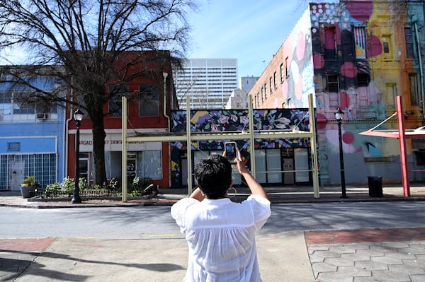 An attendee takes a picture of buildings during a walking tour of South Downtown Atlanta in March 2024. (Hyosub Shin/AJC)