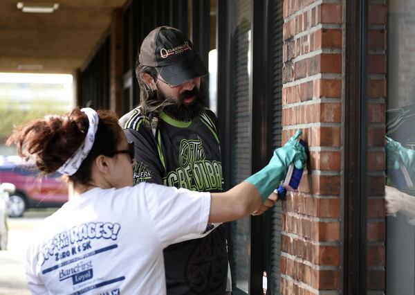 Volunteers Emily Nicholls and Andy Jacobs use brushes to clean the wall outside the Democratic Party office in Norman, Oklahoma, where racist, anti-gay and anti-Semitic graffiti was found on Wednesday, April 3, 2019. The building, a school and an art center were hit with graffiti the night before. Allison Christine Johnson, 45, of Norman, is accused of vandalizing buildings in Oklahoma City and Norman over the span of several weeks. Johnson turned herself in to police Thursday, April 4.