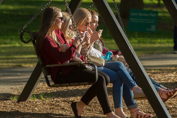 Morgan Haynes, Baily St. Germain, Kaley St. Germain, Logan St. and Germain, sit on a swing looking out over the lake at Piedmont Park during the 80th Annual Atlanta Dogwood Festival in Midtown. STEVE SCHAEFER / SPECIAL TO THE AJC