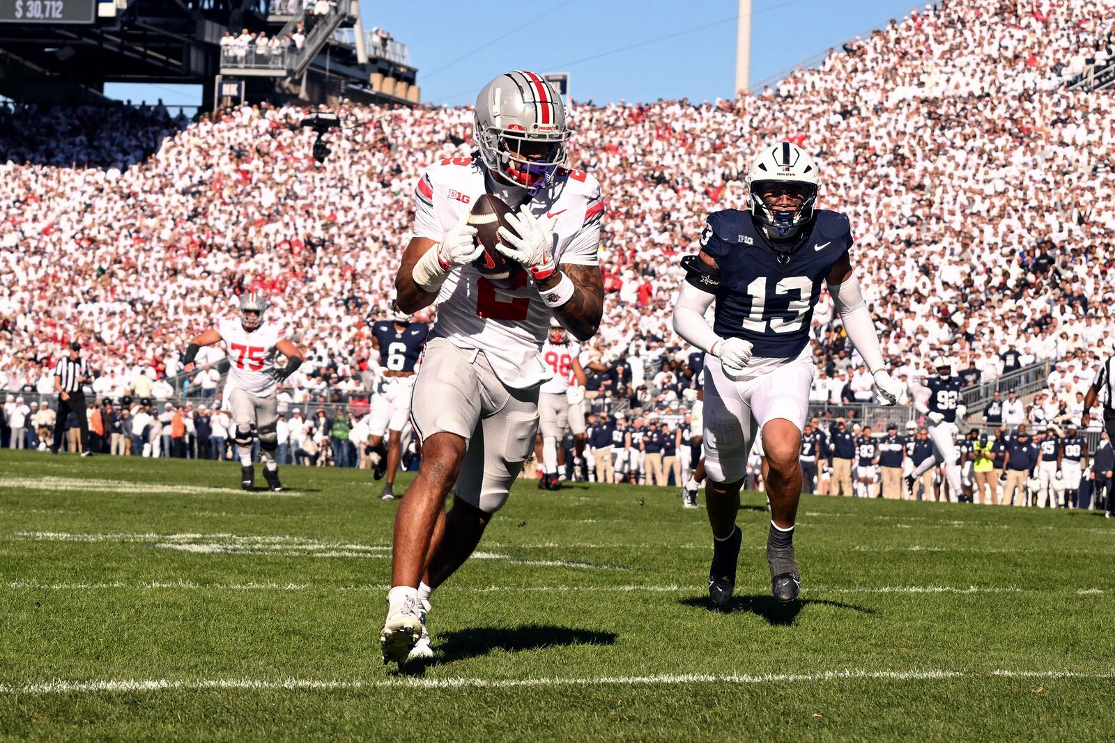 Ohio State wide receiver Emeka Egbuka (2) catches a touchdown pass in front of Penn State linebacker Tony Rojas (13) during the first quarter of an NCAA college football game, Saturday, Nov. 2, 2024, in State College, Pa. (AP Photo/Barry Reeger)