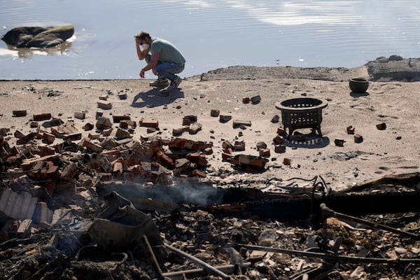 Luke Dexter kneels in front of his father's fire-ravaged beach front property in the aftermath of the Palisades Fire Friday, Jan. 10, 2025 in Malibu, Calif. (AP Photo/John Locher)