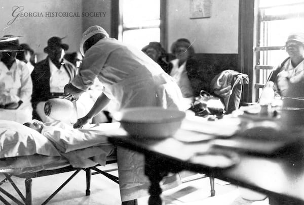 Midwife Georgia Barron conducts a demonstration during a midwife class in 1938. Barron, who practiced as a midwife from 1898-1938, uses a pitcher with a manikin in preparation for childbirth. The photo's original caption states that "The necessity for cleanliness is emphasized." (Courtesy of the Georgia Historical Society, MS 55-VM01-02-556)