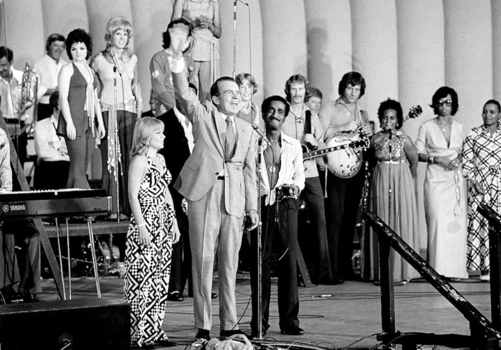 resident Richard M. Nixon waves to an estimated 8,000 of his supporters at a youth rally in Marine Stadium on Aug. 22, 1972, in Miami Beach after the Republican National Convention nominated him for reelection. With him are Pam Powell, head of Young Voters for the President, and Sammy Davis, Jr., the rally master of ceremonies. (AP)