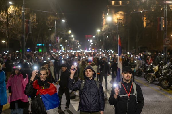 People use the lights on their cell phones as they observe fifteen minutes of silence during a major anti-corruption rally led by university students in Belgrade, Serbia, Saturday, March 15, 2025. (AP Photo/Marko Drobnjakovic)