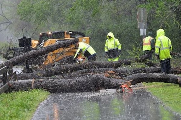 Workers clean up fallen trees on Azalea Drive near Avia Riverside Apartments in Roswell on Wednesday. HYOSUB SHIN / HSHIN@AJC.COM