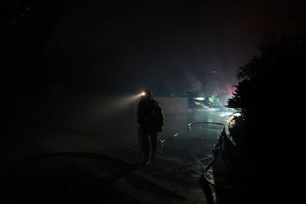 A firefighter carries a water hose while tackling the Franklin Fire in Malibu, Calif., Tuesday, Dec. 10, 2024. (AP Photo/Jae C. Hong)