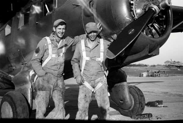 Sgt. Jim Galloway, left, in greasy overalls and a parachute.