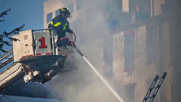 Firefighters continue to spray water onto a smoldering building in the aftermath of a fire Wednesday, Oct. 3, 2018, in Manhattan's East Village. The fire started around 2 a.m. Wednesday on the first floor and continued into the morning.