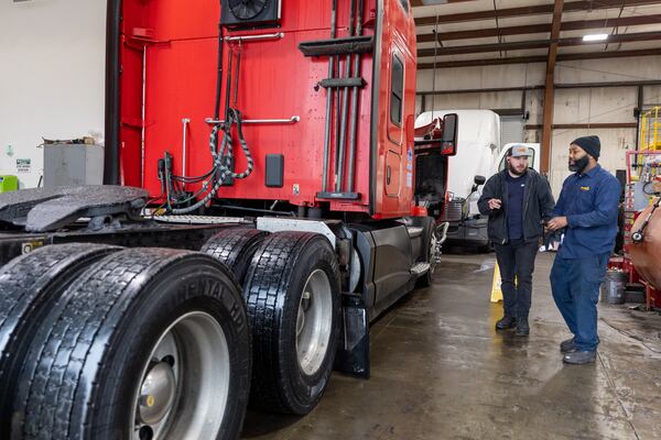 Employees talk at Status Truck & Trailer Repair in Forest Park on Wednesday, January 24, 2024. (Arvin Temkar / arvin.temkar@ajc.com)