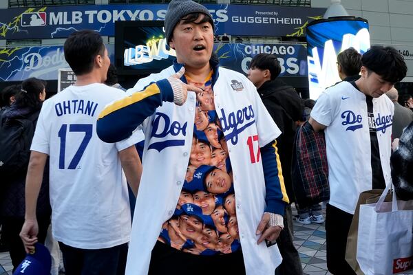 A fan shows a shirt featuring Los Angeles Dodgers' Shohei Ohtani before an MLB Japan Series baseball game between the Los Angeles Dodgers and the Chicago Cubs at Tokyo Dome, in Tokyo, Tuesday, March 18, 2025. (AP Photo/Shuji Kajiyama)