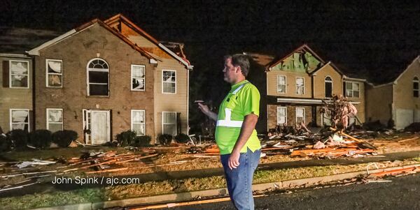 Cal Welk with Champion Construction looks at damage on Jumpers Trail in Fairburn. JOHN SPINK / JSPINK@AJC.COM