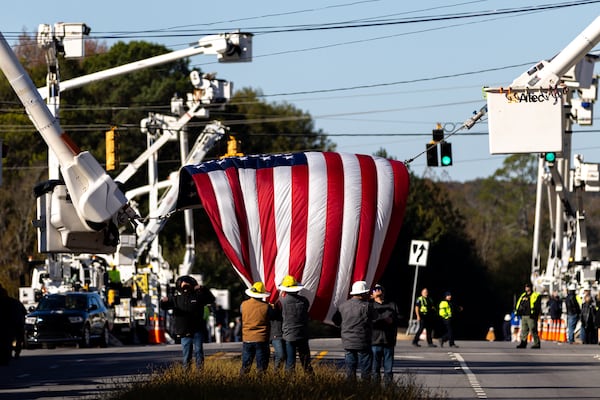 Linemen remove an American flag following a funeral procession Thursday in Griffin in honor of Eric Weems. He died last week after an equipment failure.