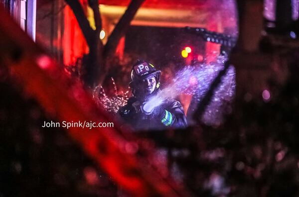 An Atlanta firefighter battles a blaze on Blake Avenue on Friday morning. The homeowners were able to get out safely.