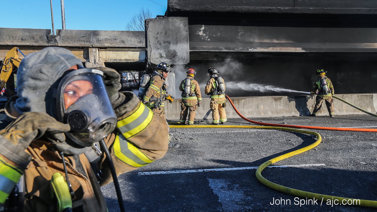 Fire crews continue to battle smoking debris at the site of the I-85 collapse Friday. JOHN SPINK / JSPINK@AJC.COM