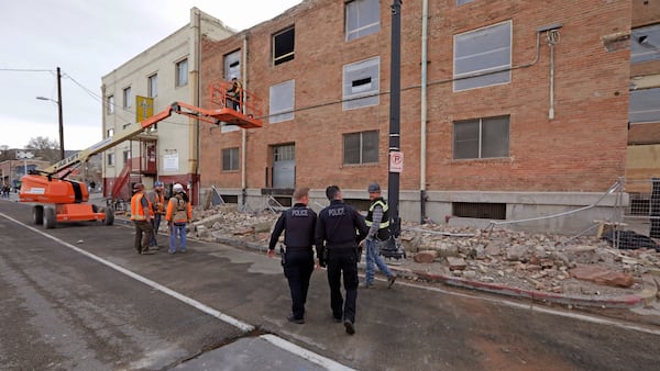 Police officers walk by rubble after a 5.7-magnitude earthquake near Salt Lake City.