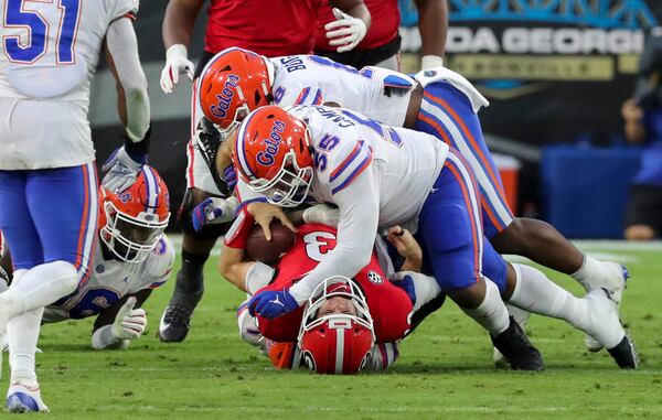 Georgia quarterback Stetson Bennett (13) is taken down at the line of scrimmage by Gators defensive lineman Kyree Campbell (55) in the first half Saturday, Nov. 11, 2020, in Jacksonville, Fla.