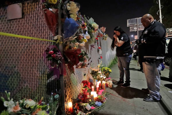 FILE - Sol Rodriguez, center, and Aaron Torres visit a shrine for the victims of a warehouse fire near the site Sunday, Dec. 4, 2016, in Oakland, Calif. (AP Photo/Marcio Jose Sanchez, File)