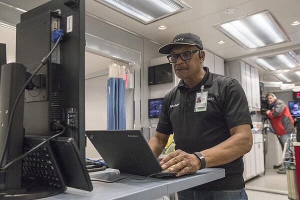 In this file photo from January, Grady Memorial Hospital Technical Support Specialist Lead Michael Hoggs prepares the data information systems inside the Carolinas MED-1, a mobile medical facility, located outside of the Marcus Trauma and Emergency room at Grady Memorial Hospital in Atlanta. The facility houses extra emergency room beds and has an operable emergency operating room to help cope with the influx of flu cases . (ALYSSA POINTER/ALYSSA.POINTER@AJC.COM)