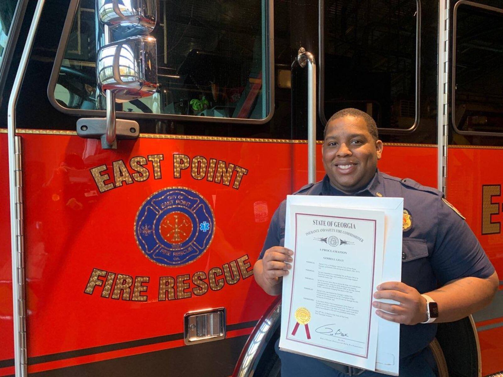 East Point Firefighter Gerrell Lilly poses with his proclamation from the state congratulating him for saving the life of Frisky the dog. (Courtesy of city of East Point)