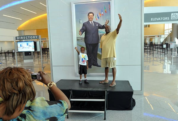 Glenn Thomas, right, of Lithonia, and his 6-year-old son Myles pose in front of Maynard H. Jackson Jr.'s portrait when the international terminal opened in 2012. (Hyosub Shin/hshin@ajc.com)