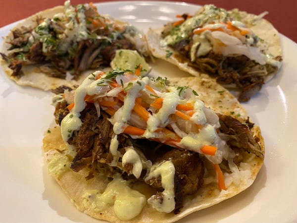 Griot tacos at Zeke’s Kitchen & Bar in Smyrna are filled with epis pulled pork, and pikliz before getting a drizzle of epis aioli. (Ligaya Figueras / ligaya.figueras@ajc.com)