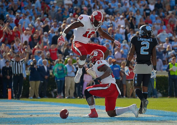 CHAPEL HILL, NC - NOVEMBER 25: Stephen Louis #12 and Matthew Dayes #21 of the North Carolina State Wolfpack celebrate after Dayes' touchdown against the North Carolina Tar Heels during their game at Kenan Stadium on November 25, 2016 in Chapel Hill, North Carolina.  (Photo by Grant Halverson/Getty Images)