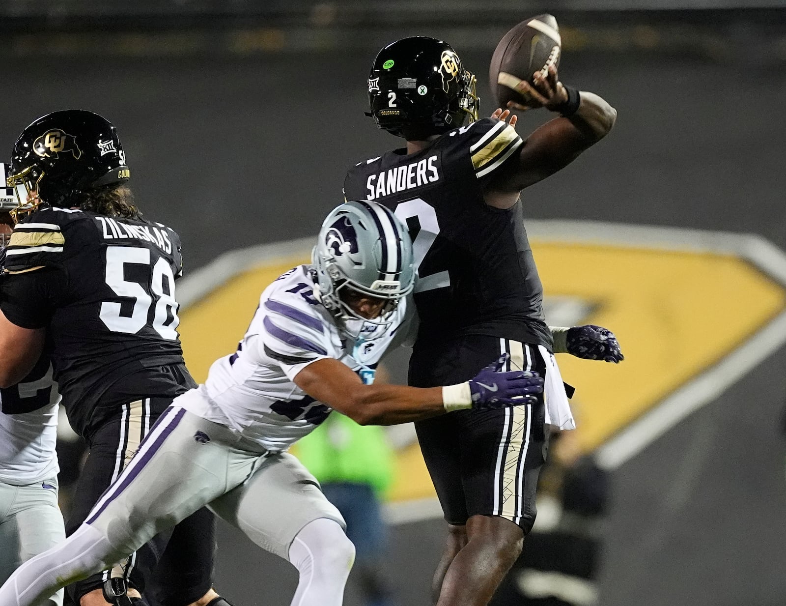 Kansas State cornerback Jacob Parrish, center, hits Colorado quarterback Shedeur Sanders, right, who prepares to release the ball in the first half of an NCAA college football game Saturday, Oct. 12, 2024, in Boulder, Colo. (AP Photo/David Zalubowski)