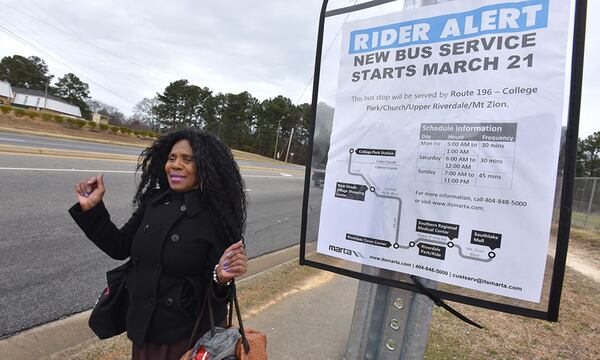 Brenda Crook celebrates as she walks past new bus stop on her way back home after her grocery shopping in Riverdale in 2015. (HYOSUB SHIN / HSHIN@AJC.COM)