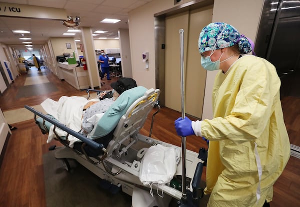 Carey Mullis, a registered nurse, moves a COVID-19 patient from the emergency room to a room on a COVID floor at Colquitt Regional Medical Center on Thursday.  Curtis Compton / Curtis.Compton@ajc.com