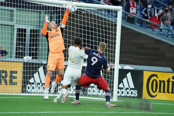 Atlanta United goalkeeper Brad Guzan (left) blocks shot on goal as defender Anton Walkes (4) holds off the attack of New England forward Adam Buska (9) during their match Saturday, May 1, 2021, in Foxborough, Mass. (MLS)