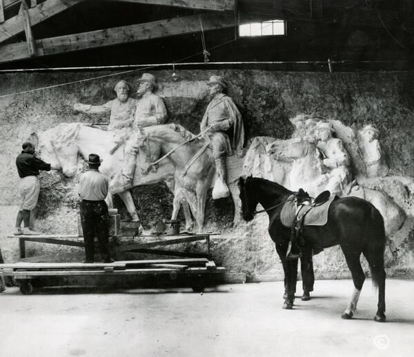 Famed sculptor Gutzon Borglum, shown here (at left) between 1923-25 with a plaster maquette of his vision for the Stone Mountain sculpture, was tasked with carving the original planned sculpture onto the face of Stone Mountain. He began his work in 1923 but his contract was cancelled in 1924. Borglum would go on to carve the figures at Mount Rushmore in South Dakota.