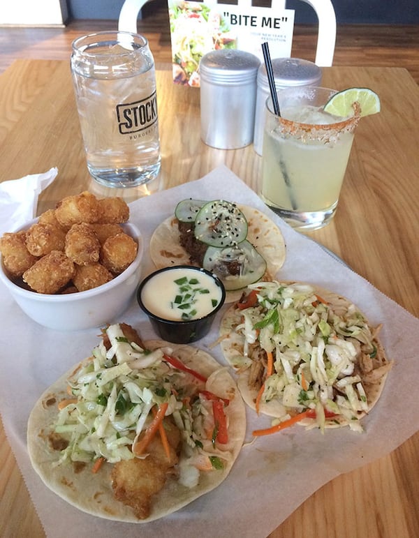 Taqueria Tsunami offers 13 tacos combining Asian and Latin favors. Among the best from our visit to the Roswell Road location are (clockwise from top) Korean barbecue short rib with cucumber salad; Vietnamese pork with Asian slaw; and Baja-style tempura-fried fish with Asian slaw and Sriracha mayo. Also shown are a side of tater tots with queso dipping sauce and the house margarita. CONTRIBUTED BY WENDELL BROCK