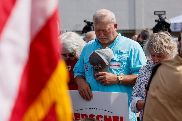 A supporter prays at a Herschel Walker’s campaign stop in Carrollton. “Herschel Walker is tapping into the community of faith and using coded language that says to white evangelical voters, ‘I’m one of you,’ ” said Andra Gillespie, a political science professor at Emory University. (Arvin Temkar / arvin.temkar@ajc.com)