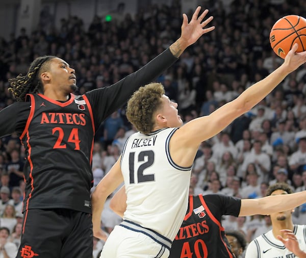 Utah State guard Mason Falslev (12) shoots as San Diego State guard Taj DeGourville (24) defends in the second half of an NCAA college basketball game Saturday, Feb. 22, 2025, in Logan, Utah. (Eli Lucero/The Herald Journal via AP)