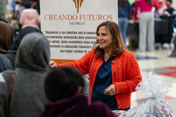 A volunteer with Creating Futures Georgia hands out winter clothing items at WeLoveBufordHighway's fifth annual Holiday Healing event at Sequoyah Middle School. Over 1,200 people attended to receive food, clothing and other resources. Saturday, December 14, 2024 (Ben Hendren for the Atlanta Journal-Constitution)