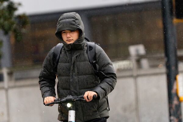 A man rides a scooter across 10th Street in Tuesday's chilly rain. (Ben Hendren for the Atlanta Journal-Constitution)