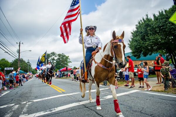 Ann Harris carries an American flag down Dacula Rd. while on horseback during the annual Dacula Memorial Day Parade on Monday, May 25, 2015. The parade, now in its 22nd year, remains the only Memorial Day parade in Metro Atlanta, largest in the the state of Georgia and one of the largest in the nation with more than 150 units participating last year. JONATHAN PHILLIPS / SPECIAL