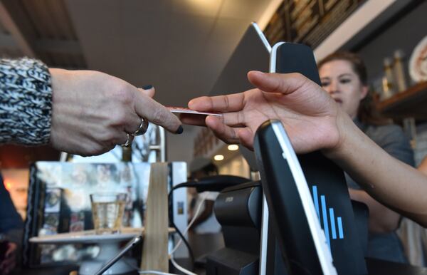 Pam Redman hands over her credit card to staffer Daylynn Brown at The Local Pizzaiolo in Atlanta. The restaurant is one of several in the area that don’t accept cash. HYOSUB SHIN / HSHIN@AJC.COM