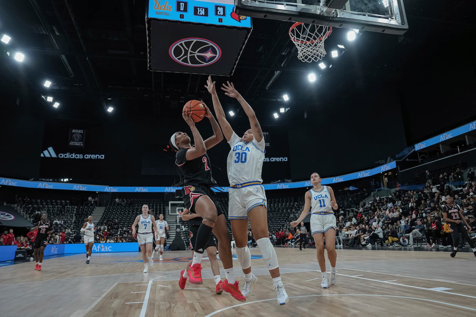 Louisville forward Nyla Harris, left, drives UCLA's forward Timea Gardiner (30) defends during an NCAA college basketball game Monday, Nov. 4, 2024, in Paris, France. (AP Photo/Aurelien Morissard)