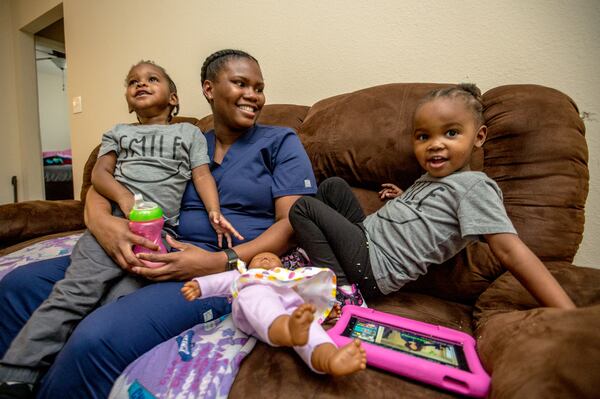 Before their dad gets home from work, Basia Taylor balances her work as a dental hygienist with one more exam to take, and her 2-year-old twins Michael, left, and Milani Blair, right. The family has adjusted through the pandemic with adjustments for child care, Taylor's education requirements and job schedules. (Jenni Girtman for The Atlanta Journal-Constitution)