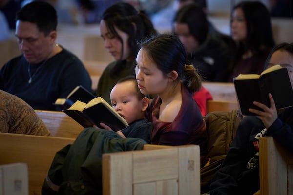 A worshipper holding her son sings during a religious service in a church in Nuuk, Greenland, Sunday, Feb. 16, 2025. (AP Photo/Emilio Morenatti)