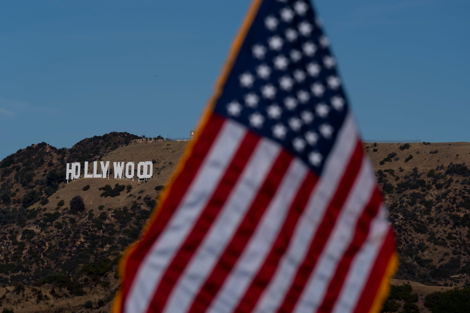 With the Hollywood sign in the background, an American flag stands during a naturalization ceremony at Griffith Observatory in Los Angeles, Monday, Oct. 21, 2024. (AP Photo/Jae C. Hong)