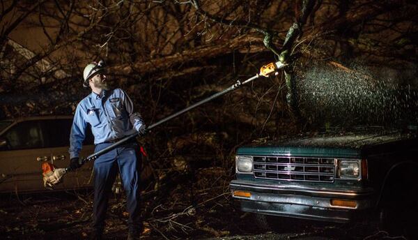 A crew worked Tuesday to restore power after a tree fell onto a home and cars on Linwood Avenue in East Point. BRANDEN CAMP / Special to AJC