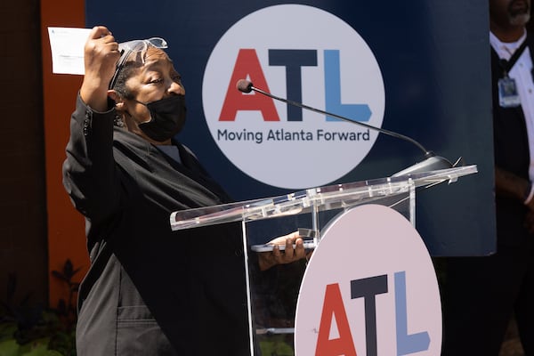 Lucy Sims with the Beautiful Restaurant holds up a grant award presented to her by Mayor Andre Dickens at a press conference Tuesday, August 30, 2022. Steve Schaefer/steve.schaefer@ajc.com)