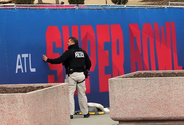 A Department of Homeland Security police officer checks the security of a fence built around Mercedes-Benz Stadium and the surrounding area for the Super Bowl on Tuesday, Jan. 22, 2019, in Atlanta. (Curtis Compton/ccompton@ajc.com)