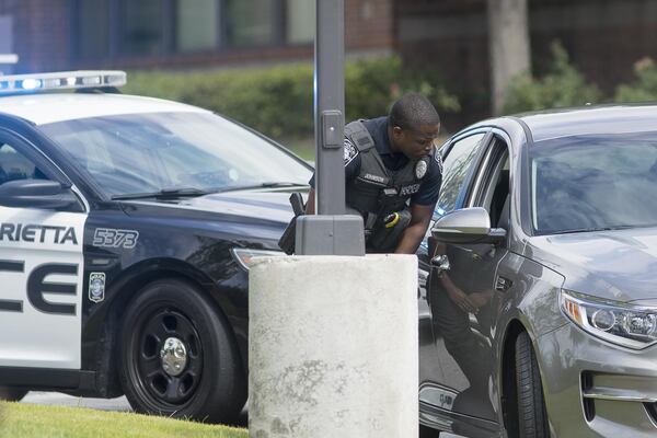 6/19/2019 — Marietta, Georgia — A Marietta Police officer issues a citation to a driver during a Marietta Police Department multi-agency distracted driving enforcement operation in Marietta, Wednesday, June 19, 2019. The operation, which involved three under-cover Marietta Police officers dressed as construction workers, took place at the intersection of US 41 and Roswell Road. When the officers saw a distracted driving violation, in addition to others, they radioed ahead and one of the forty officers involved in the operation issued a citation to the driver. (Alyssa Pointer/alyssa.pointer@ajc.com)